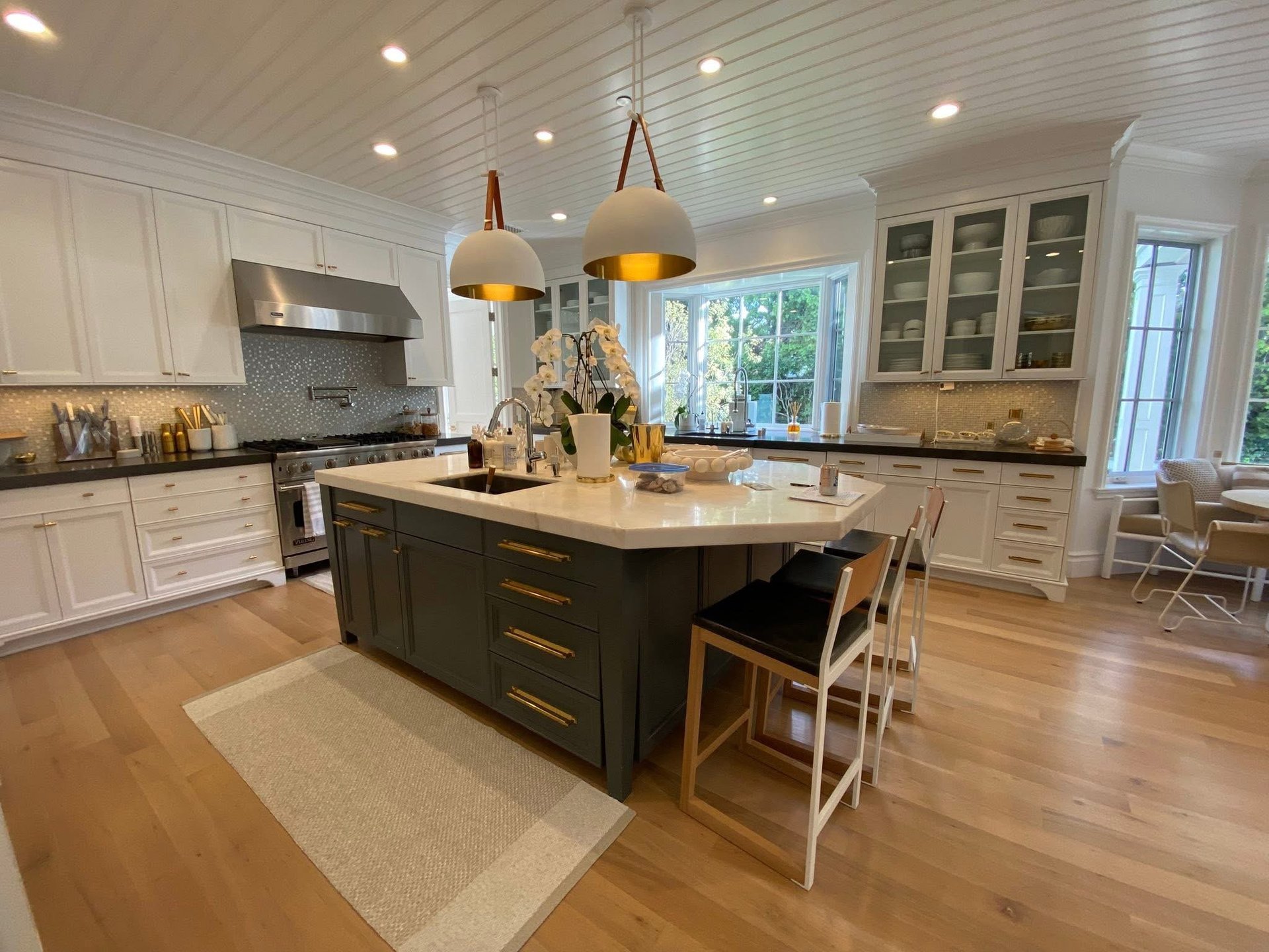 Modern kitchen with white cabinetry, dark island, pendant lights, and wooden flooring