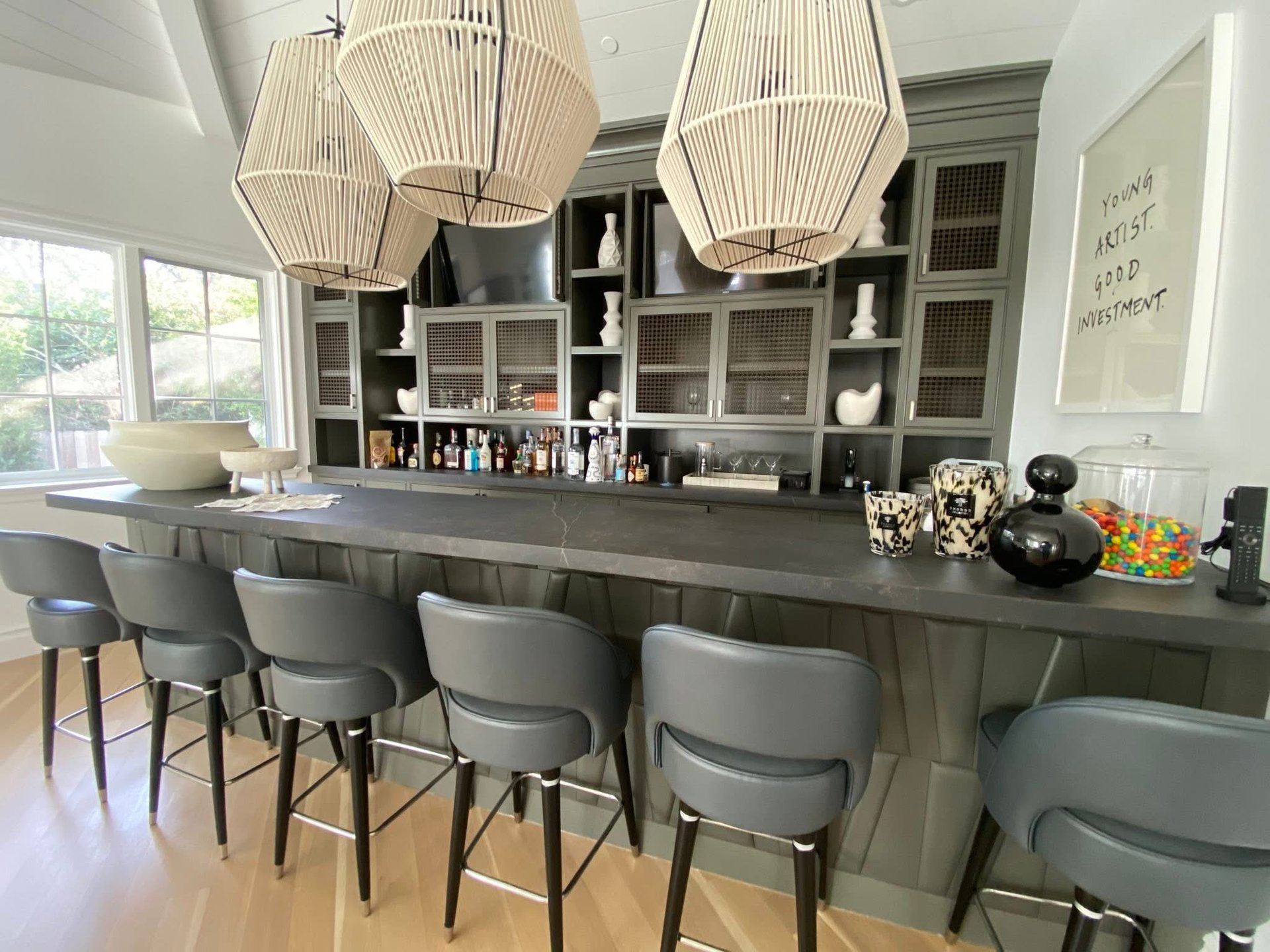 Modern kitchen with gray island, bar stools, pendant lights, and wall shelving